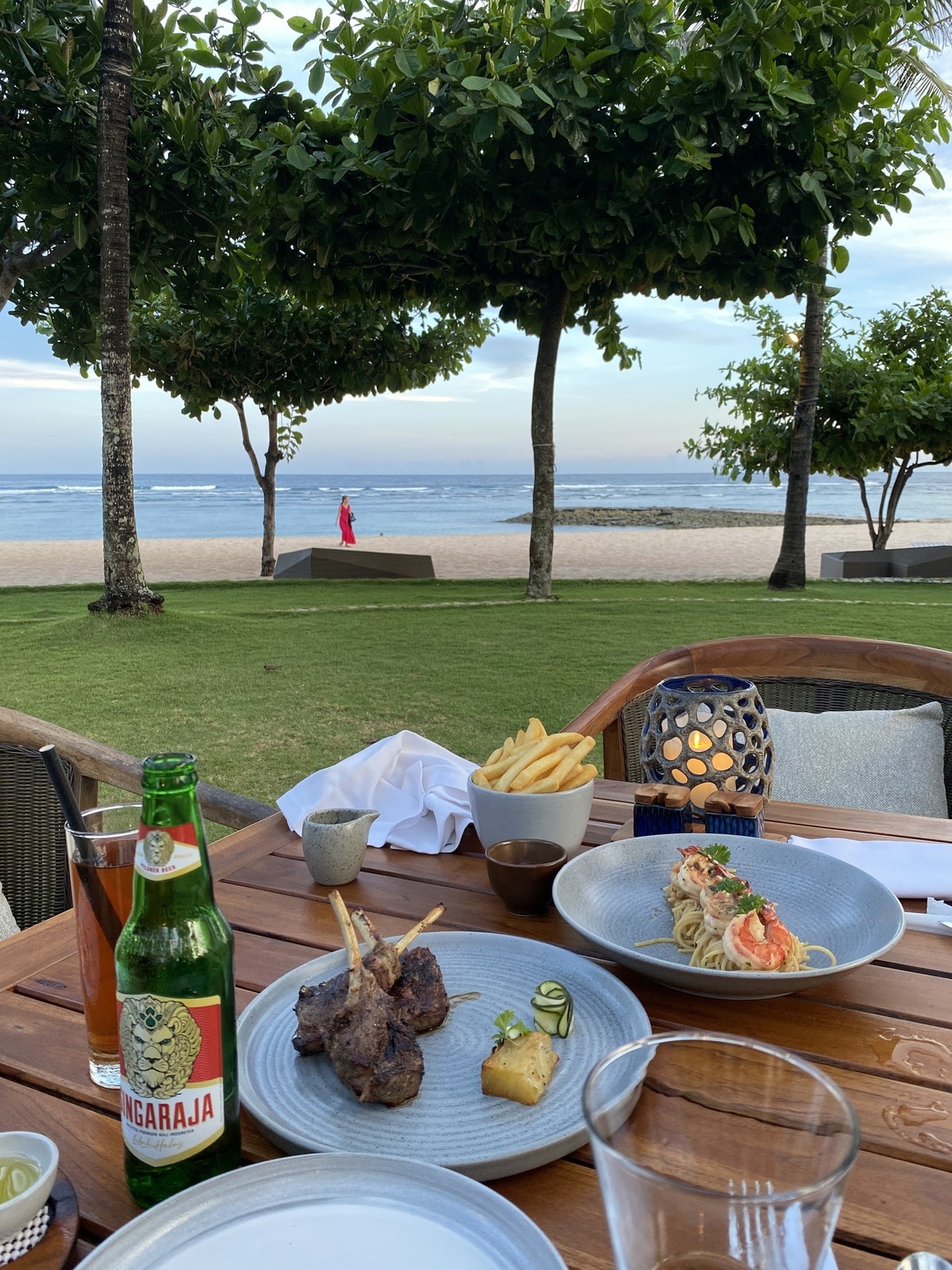 ビーチグリルの屋外テーブルに並ぶ夕食と海辺の景色