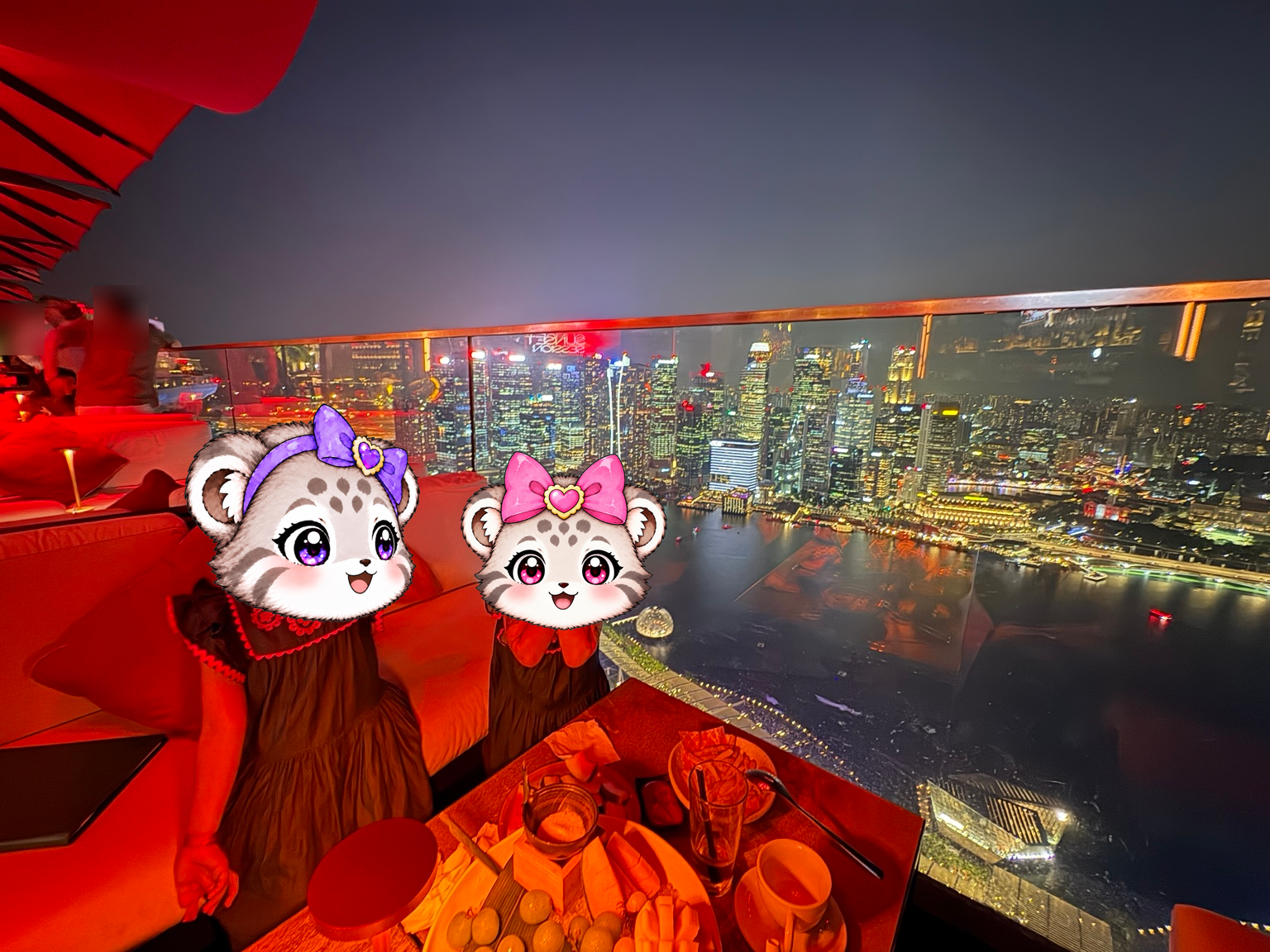 高層ビル群の夜景を背景に記念撮影するこまぬとこみぬ