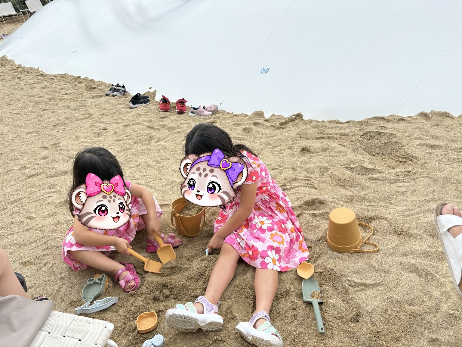 ふわふわドームのそばの砂場で遊ぶ姉妹